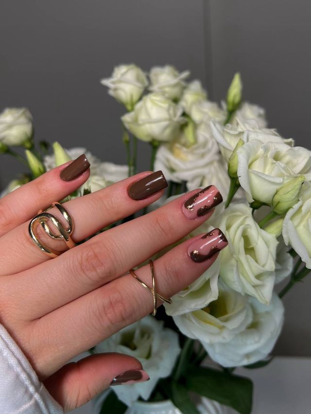 Chocolate brown nails, two of them with a nude-and-brown swirl and gold leaf