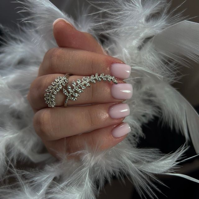 Soft pink square nails, with white feathers beside them