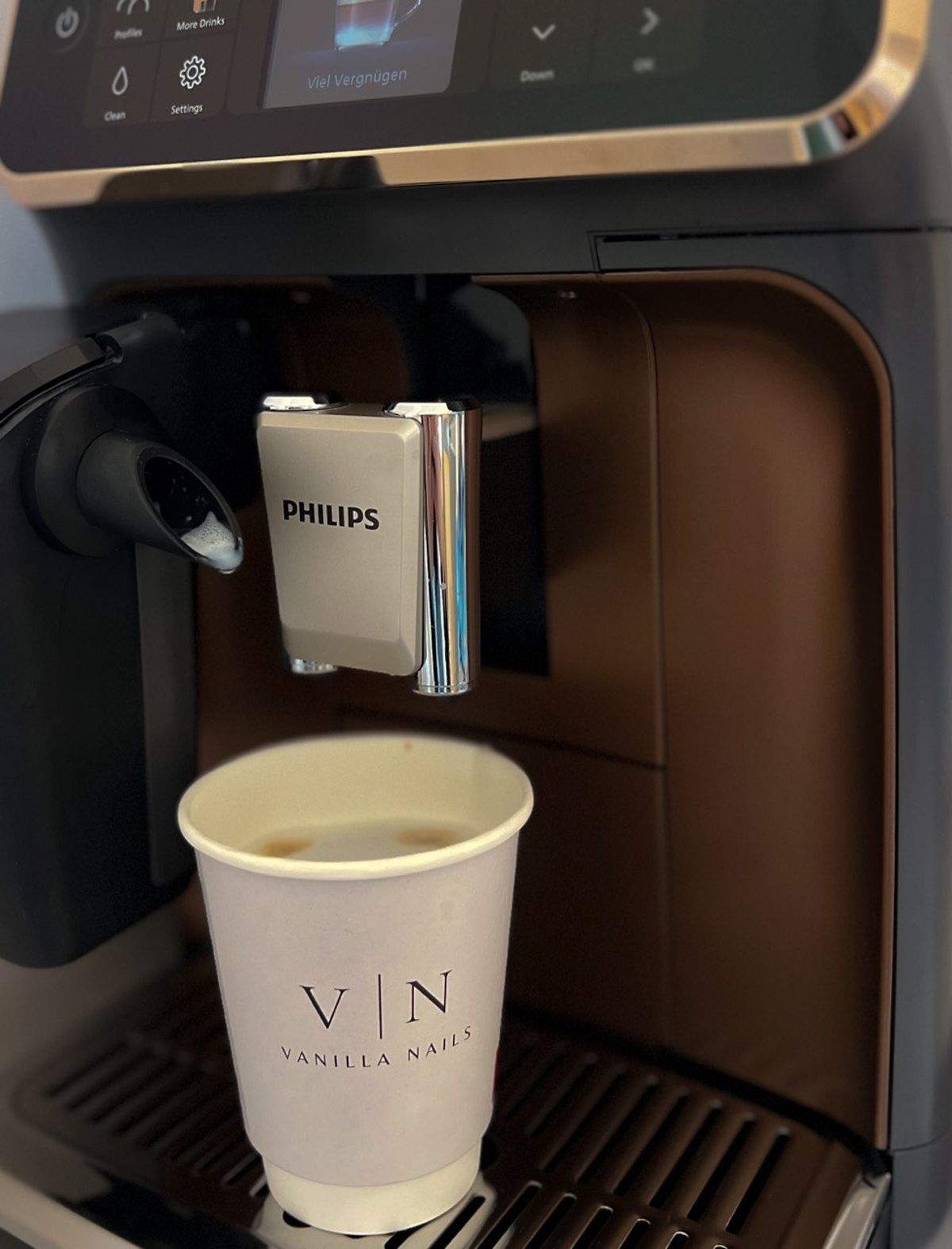 Kaffeebecher mit Vanilla-Nails-Logo an der Kaffeemaschine